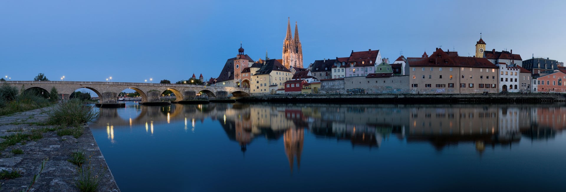 Panorama der Regensburger Altstadt zur blauen Stunde mit Steinerner Brücke, Dom und Spiegelung in der Donau